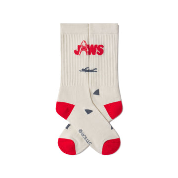 Beige socks with red accents and 'JAWS' logo on a white background. JAWS 50th ANNIVERSARY | ACADEMY MUSEUM